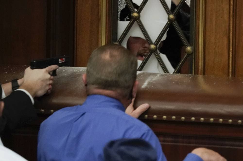 شرطي يوجه سلاحه إلى المقتحمين. «أ.ب »