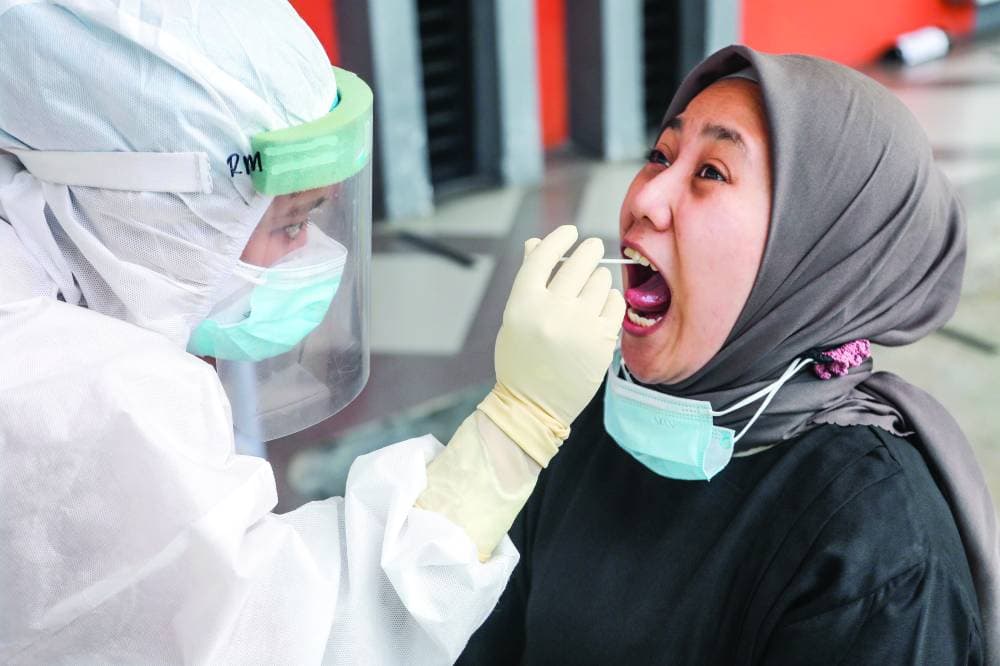 ممارسة صحية تأخذ مسحة من سيدة في مدينة مدان الإندونيسية.      'إ. ب. أ'