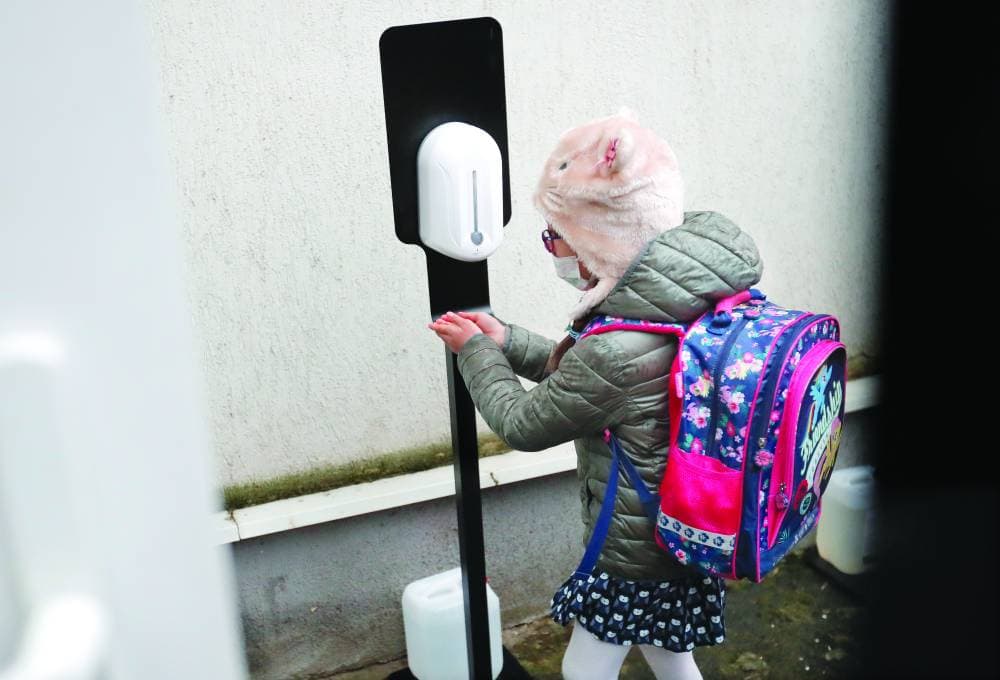 طفلة تعقم يديها في مدخل إحدى مدارس العاصمة الرومانية بوخارست.     'إ. ب. أ'