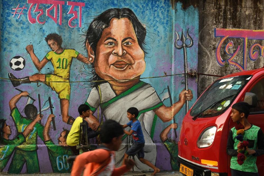 أطفال يمرحون أمام جدارية تصور ماماتا بانيرجي رئيسة وزراء غرب البنغال قبل انتخابات المجلس التشريعي، في كلكتا الهندية."الفرنسية"