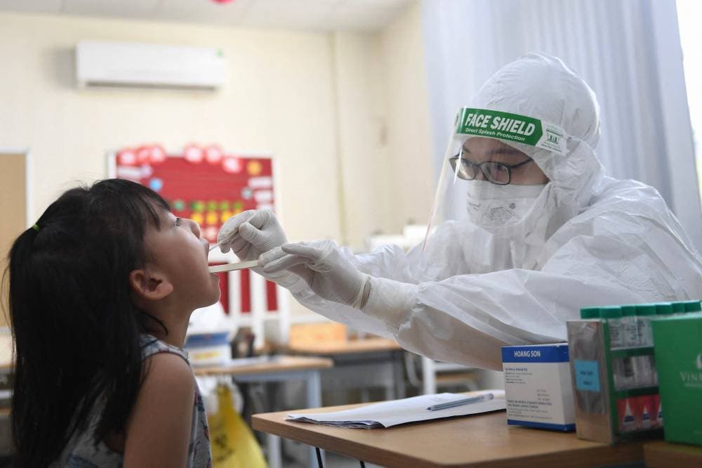 ممارس صحي يأخذ مسحة للفحص من طالبة في إحدى مدارس العاصمة الفيتنامية هانوي. «الفرنسية»