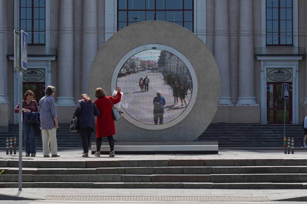 أشخاص يتفاعلون مع شاشة فيديو نصبت في مدينة لوبلان البولندية، تعرض لهم أشخاصا من مدن أخرى. "رويترز"