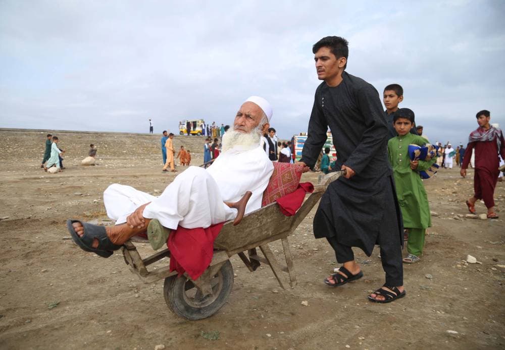  أفغاني يدفع عربة صغيرة تحمل والده خلال الذهاب لصلاة العيد."إ.ب.أ"