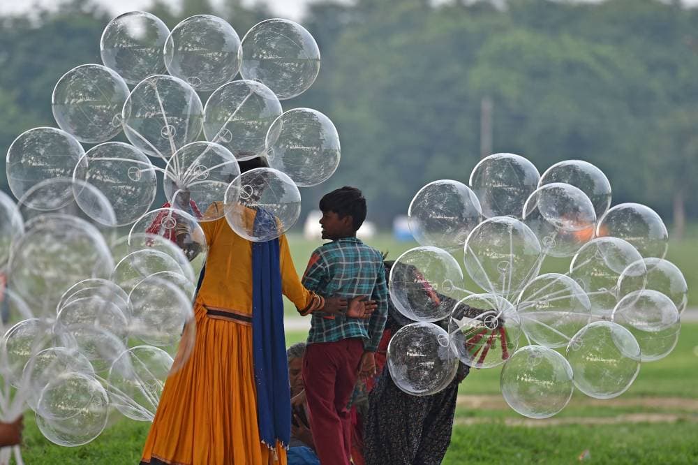 باعة جائلون على جانب الطريق يحملون بالونات في ولاية أوتار براديش شمال الهند. «الفرنسية »