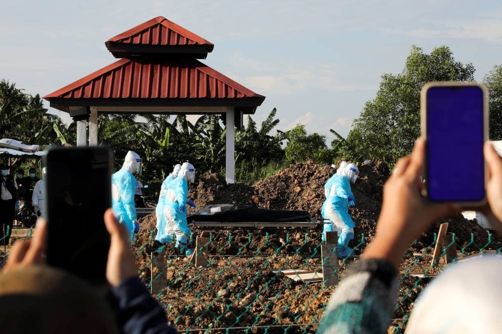 

عمال صحيون يدفنون اشخاصا توفوا جراء الإصابة بكوفيد-19 في كلانج، ماليزيا."رويترز"







