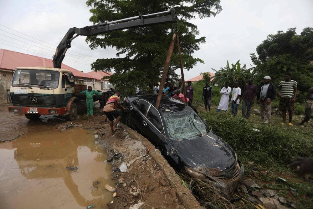أشخاص يحاولون سحب سيارة جرفتها مياه الفيضانات التي دمرت عدة منازل بعد هطول أمطار غزيرة في العاصمة النيجيرية أبوجا. «الفرنسية »