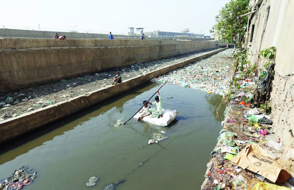 أطفال يبحثون في قناة مياه الصرف الصحي عن مواد قابلة لإعادة التدوير لبيعها في مدينة كراتشي الباكستانية. «الفرنسية »