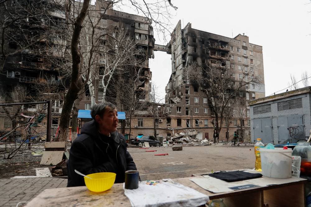 أوكراني يجلس أمام أحد المباني المدمرة في ماريوبول. «رويترز»