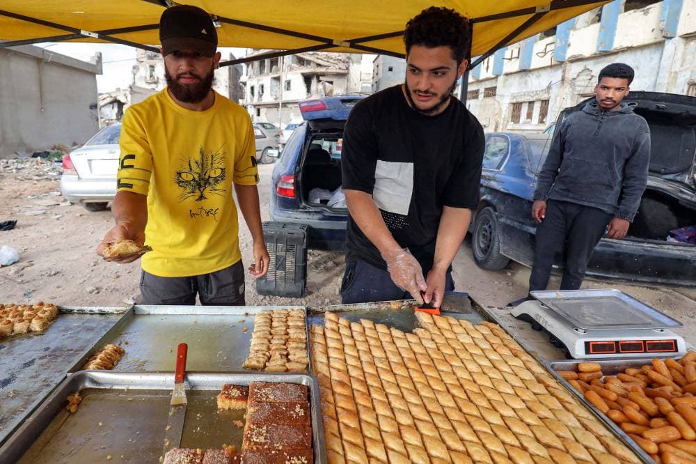 باعة جائلون يقطعون حلوى للبيع في سوق في مدينة بنغازي شرقي ليبيا. "الفرنسية"
