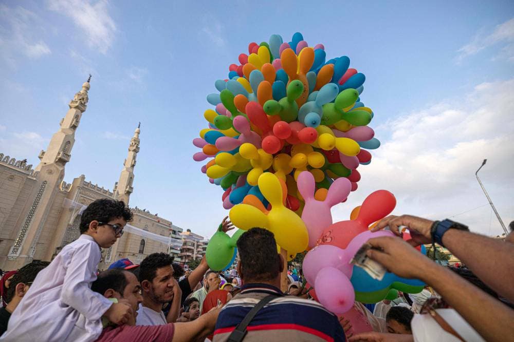 مصريون يوزعون بالونات بعد تأديتهم صلاة عيد الأضحى في القاهرة. » الفرنسية «