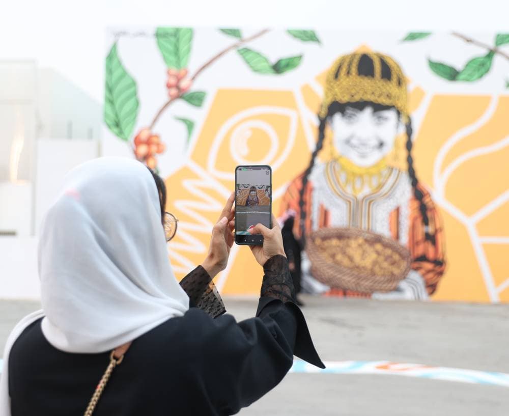 إحدى الزائرات تلتقط صورة تذكارية لعمل فني.