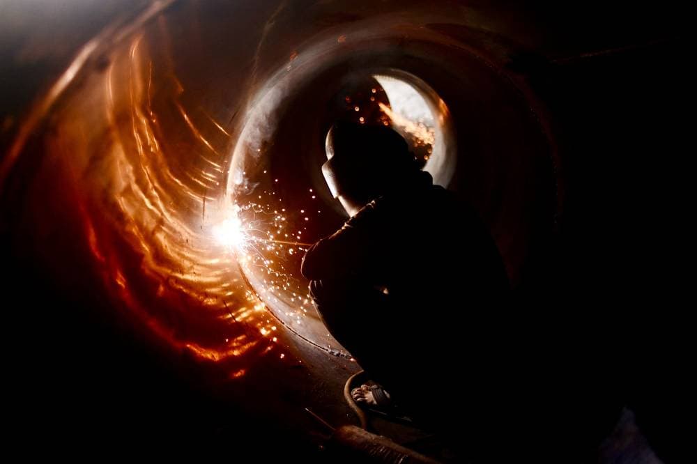 رجل يقبع في جوف أسطوانة معدنية للحمها، واستخدامها في البناء -شيتاغونغ، بنجلادش."الفرنسية"