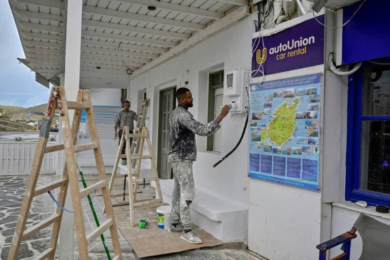 عامل يقوم بطلاء واجهة فندق في ناوسا بجزيرة باروس اليونانية استعداد لاستقبال الزوار. "الفرنسية"