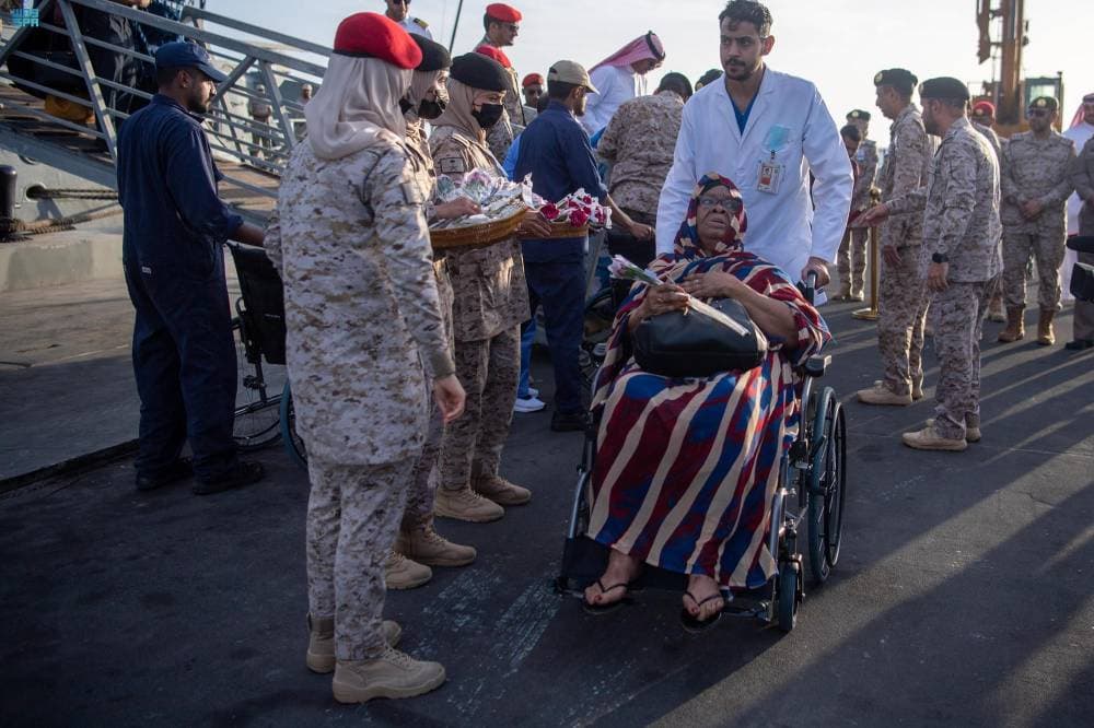 فلسطينية وطفلها يقفان أمام نافذة مركز توزيع مساعدات 