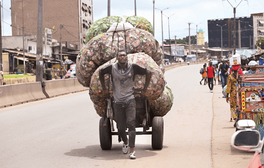 رجل يجر عربة محملة بأكياس مليئة بالعلب الفارغة في ساحل العاج