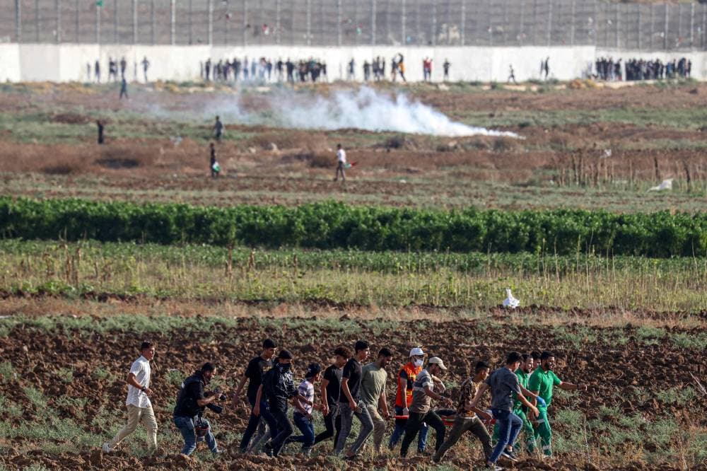 فلسطينيون يحملون مصابا بالقرب من حدود غزة. «الفرنسية»