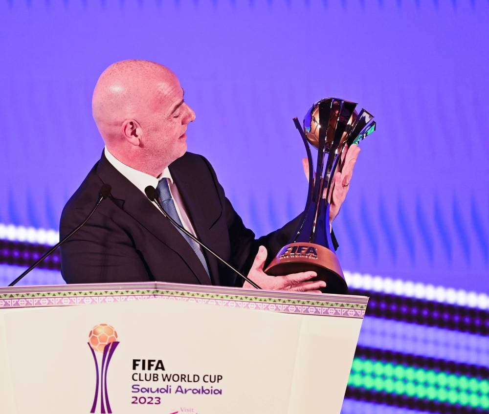 رئيس الفيفا يحمل كأس العالم للأندية.