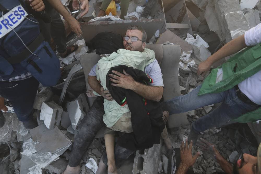 فلسطيني يحتضن طفلا بعد إخراجه من تحت الأنقاض. "أ. ب"
