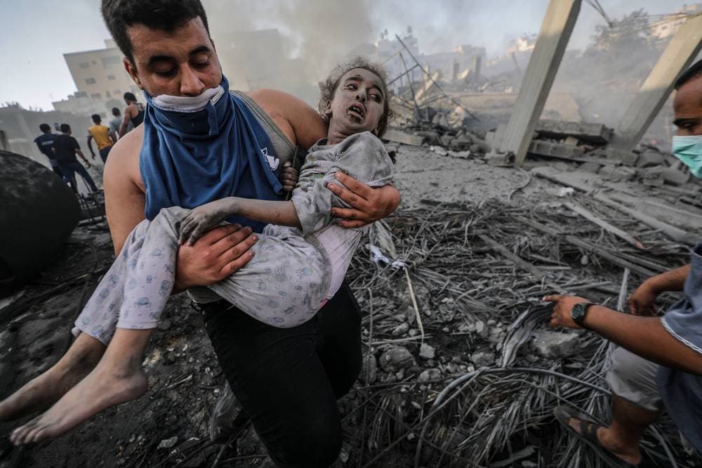 فلسطيني ينتشل طفلة من تحت الأنقاض.      "إ. ب"