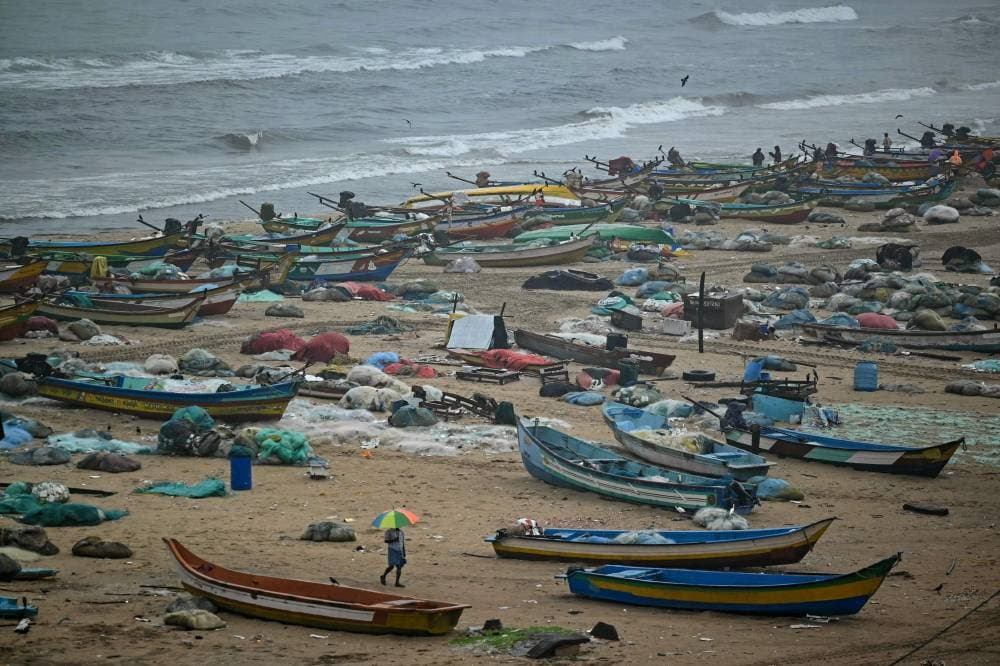  رجل يحمل مظلة يسير بجوار قوارب راسية على شاطئ مارينا، حيث يتوقف الصيد حتى انتهاء هطول الأمطار في تشيناي، الهند. "الفرنسية" 