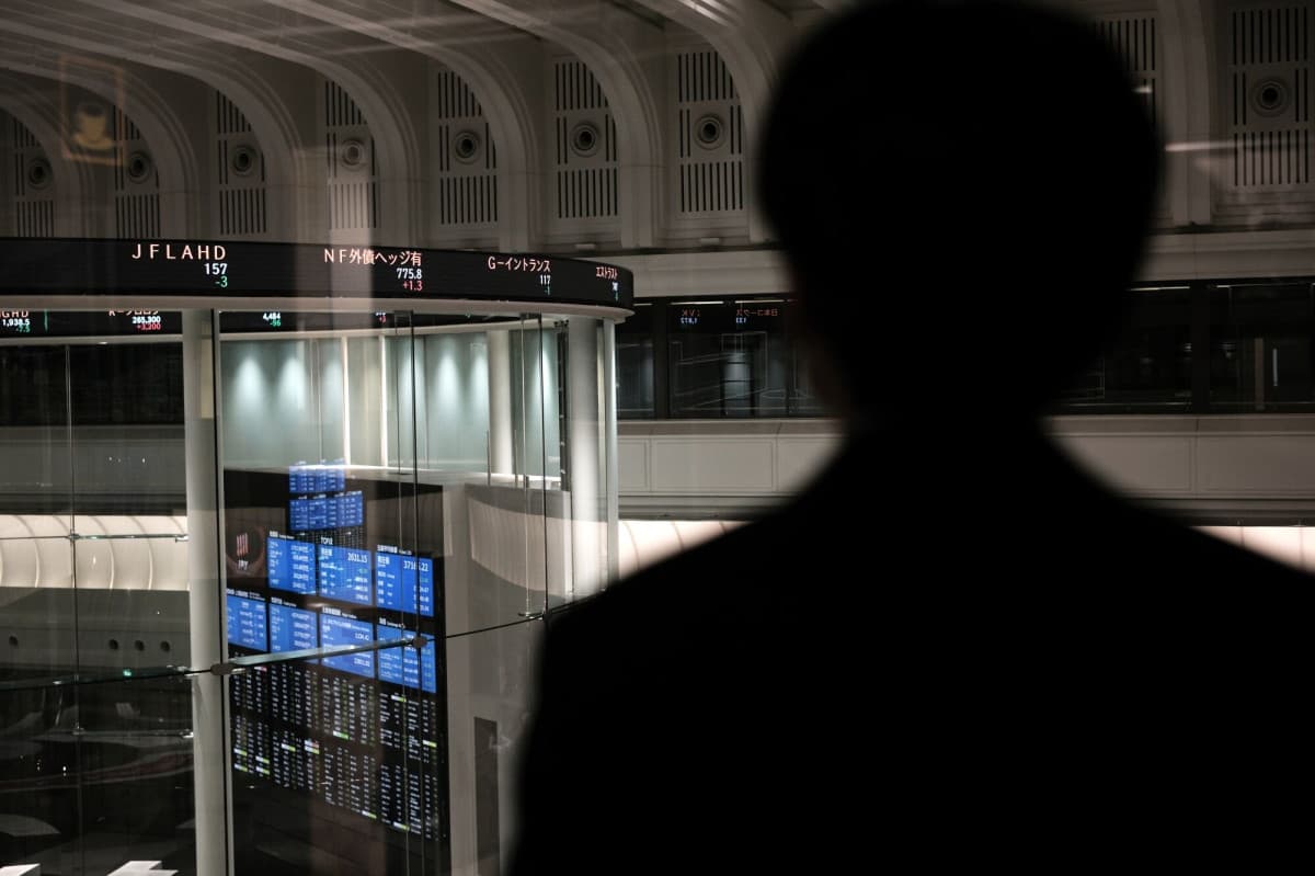 شخص يقف أمام لوحة إلكترونية تظهر بيانات الأسهم في بورصة طوكيو. "بلومبرغ"