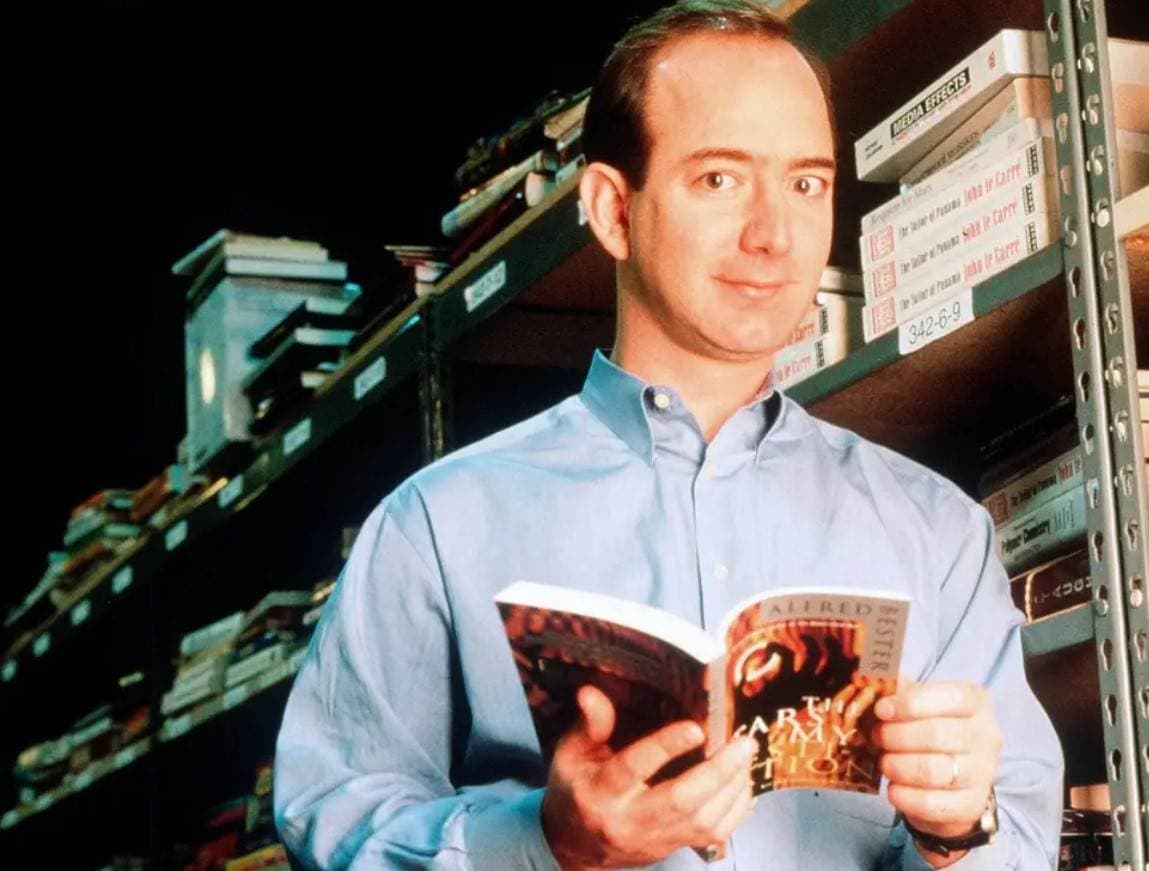 جيف بيزوس مؤسس موقع أمازون يحمل كتابا في أحد مستودعات أمازون في سياتل، واشنطن. "غيتي"