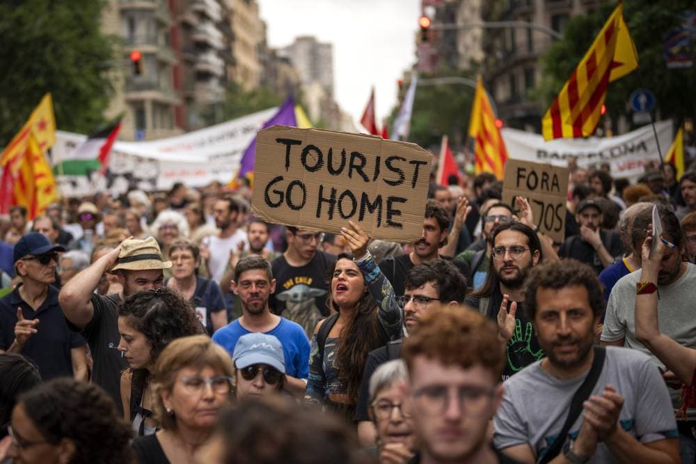 Demonstrators march shouting slogans against the Formula 1 Barcelona Fan Festival in downtown Barcelona, Spain, Wednesday, June 19, 2024. Barcelona City Hall announced last month that it would not renew any tourist apartment licenses after they expire in 2028. (AP Photo/Emilio Morenatti)