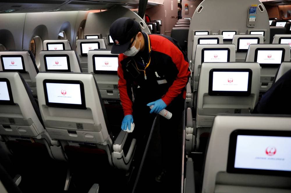 FILE PHOTO: A staff member of Japan Airlines wearing a protective face mask and gloves cleans the cabin of a plane after performing a domestic flight as passengers disembarked at Haneda airport on the first day after the Japanese government lifted the state of emergency, in Tokyo, Japan May 26, 2020. REUTERS/Kim Kyung-Hoon