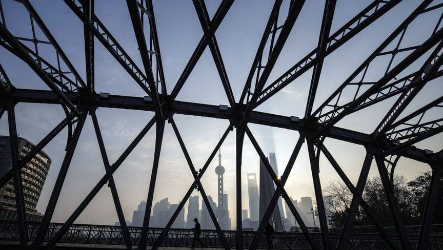 أحد المشاة يمر على جسر بين مبان في منطقة لوجيازوي المالية بشنغهاي. "بلومبرغ"