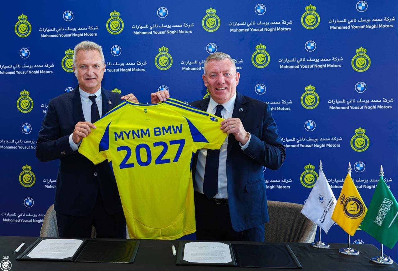 الإيطالي جويدو فينجا الرئيس التنفيذي لنادي النصر وديفيد مكفولدريك المدير العام لشركة BMW يحملان قميص النادي بعد توقيع عقد الشراكة. (مركز النصر الإعلامي)