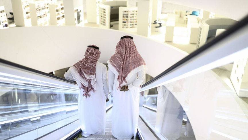 رجلان يستخدمان سلما متحركا للتنقل داخل مركز "إثراء" في الظهران. "بلومبرغ"