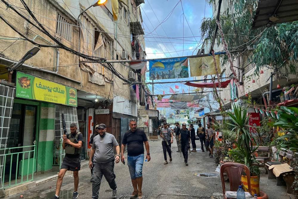 Gunmen walk in an alley of the Ain al-Helweh camp for Palestinian refugees on the outskirts of the southern port city of Sidon early on October 1, 2024, following an overnight Israeli airstrike. The strike hit "the house of the son of Mounir Maqdah," a commander of the Lebanese branch of Fatah's armed wing, a Palestinian camp official said. (Photo by Mahmoud ZAYYAT / AFP)