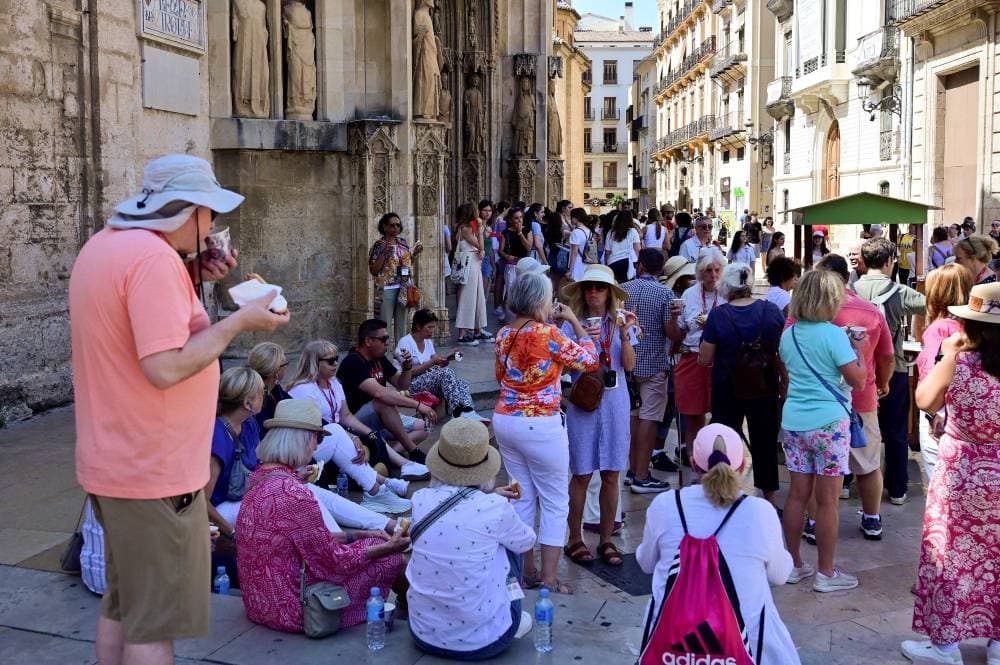 (FILES) A group of tourists take a snack in a street of Valencia on July 5, 2024. Spain this summer has been visited by 21,8 millions million international tourists, a figure 7,3% percent higher than the numbers visiting in summer 2023, establishing a new record, according to the Spanish statistics national Institute (Instituto Nacional de Estadistica - INE). (Photo by Jose Jordan / AFP)