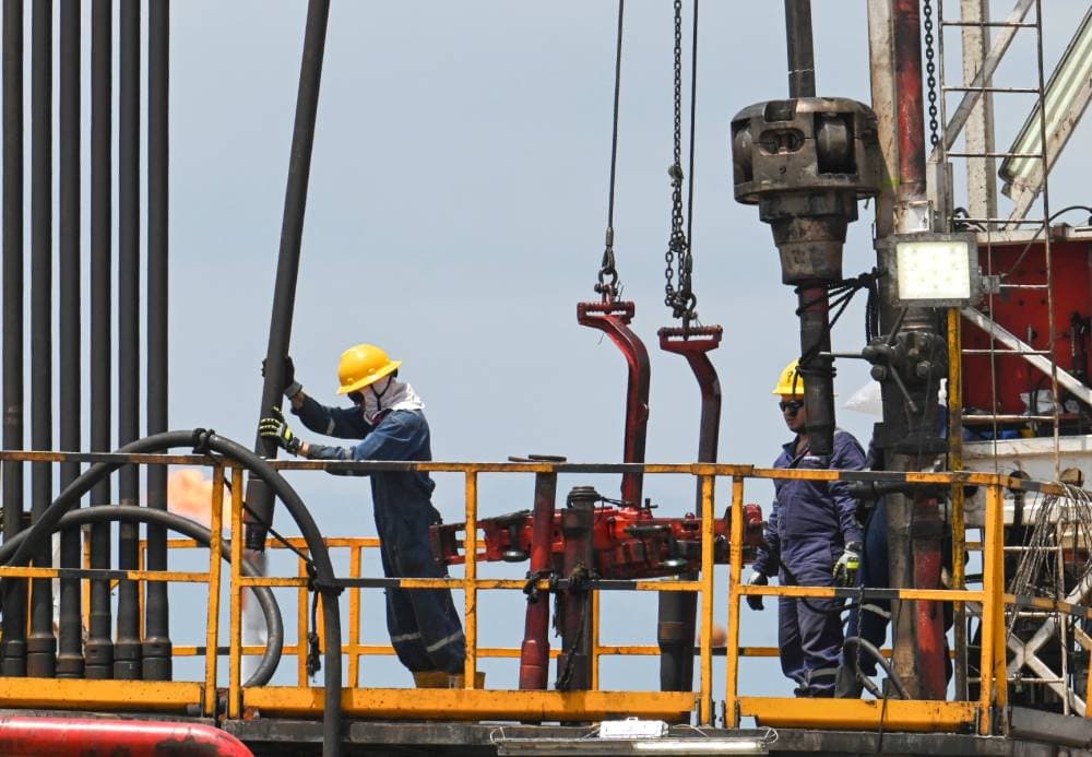 Employees work with pipelines during the extraction of crude oil at a plant of Colombian petroleum company Ecopetrol in Acacias, Meta Department, south of Bogota on February 10, 2023. (Photo by Juan BARRETO / AFP)