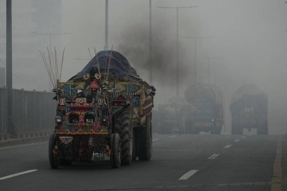  عربة جرار تطلق الدخان وتتحرك على الطريق بينما يلف الضباب الدخاني المنطقة في لاهور، باكستان. أ ب