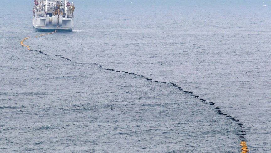 فنيون يمدّون كابلا بحريا - المصدر: بلومبرغ
