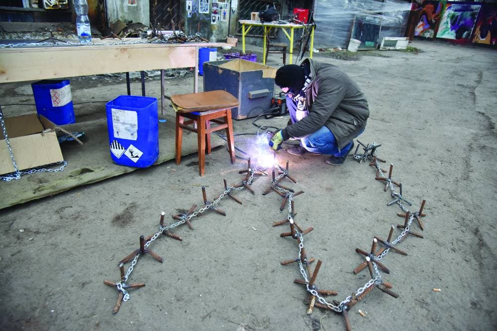 متطوع يجهز أداة لعرقلة تقدم المركبات العسكرية في مدينة لافيف الأوكرانية. "رويترز"