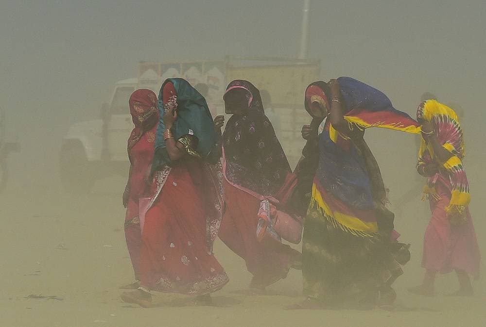 هنديات يسرن وسط عاصفة رملية تغطي الأجواء، بالقرب من أحد الأنهار في مدينة الله أباد. "الفرنسية"
