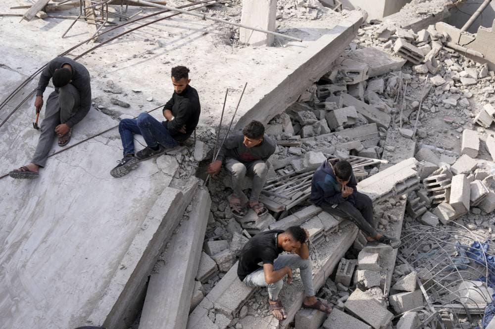 فلسطينيون يجلسون على أنقاض مبنى مدمر في مخيم النصيرات للاجئين."أ.ب"