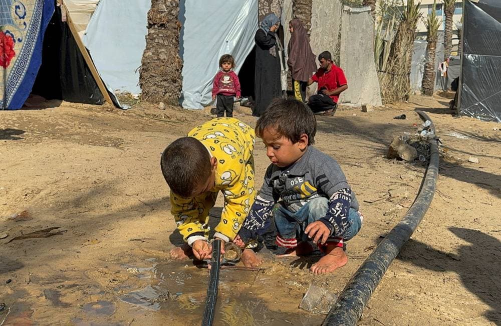 طفلاتن يحاولان الحصول على الماء من أنبوب في مخيم للجوء."رويترز"