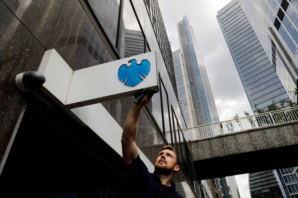 رجل ينظف لافتة خارج فرع بنك باركليز في مدينة لندن. "الفرنسية"