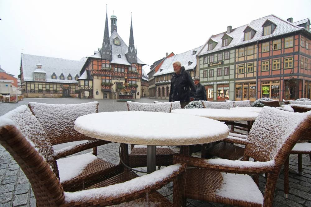 epa04976933 Tables and chairs at a cafe are covered with snow on the market square with the town hall seen in background in Wernigerode, Germany, 14 October 2015. Temperatures dipped to below zero degrees overnight with snowfall also reaching low lying areas. EPA/MATTHIAS BEIN
