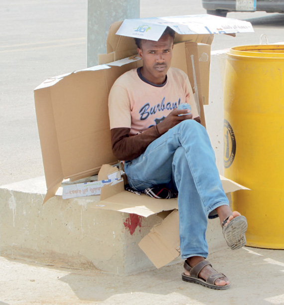 أحد الأشخاص لم يجد إلا أوراق الكرتون للحماية من الشمس.