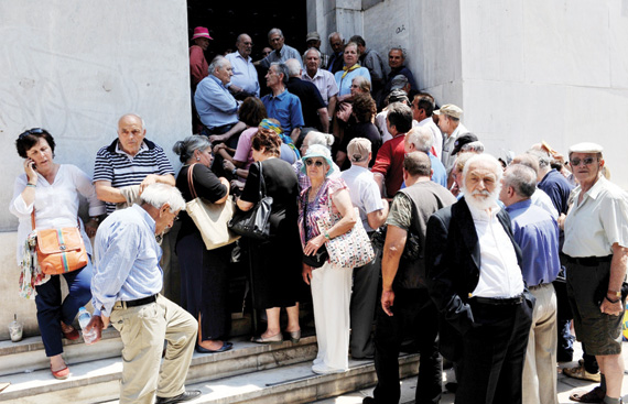 متقاعدون يونانيون ينتظرون أمام فرع مغلق لمصرف اليونان الوطني في أثينا التي تتضاعف معاناة متقاعديها بسبب أزمة البلاد المالية. جتي