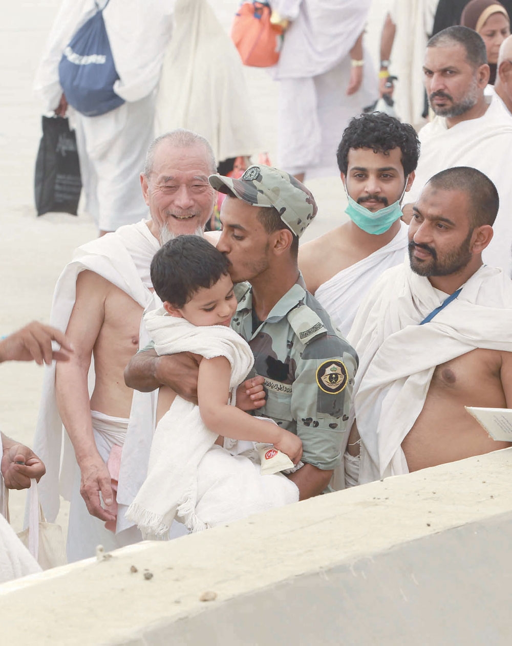 قبلة من أحد رجال الأمن لطفل يعكس مدى العناية والاهتمام بالحجيج. تصوير: عدنان مهدلي - "الاقتصادية"