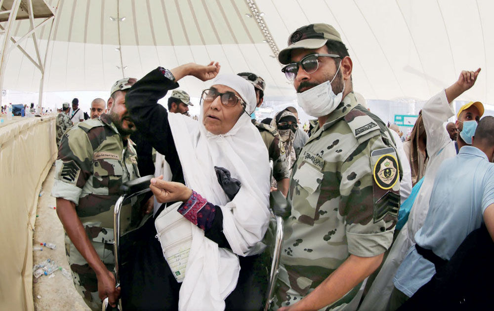 رجلا أمن يساعدان حاجة مسنة على رمي الجمرات أمس.تصوير: أحمد حشاد - "الاقتصادية"