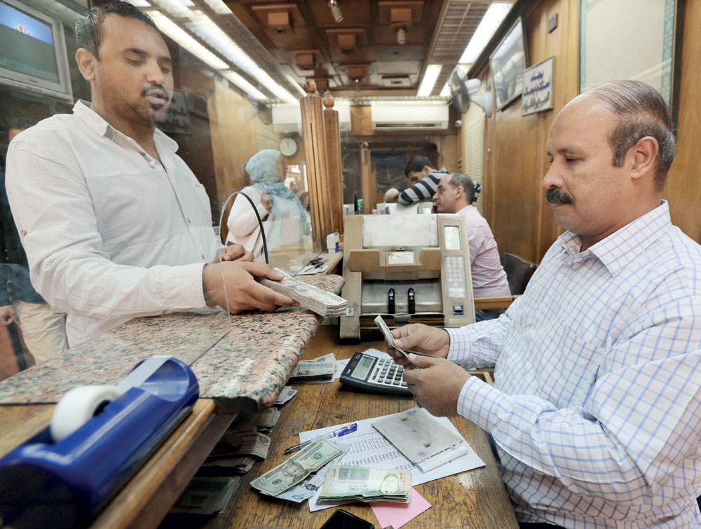 عملاء يقومون بتبديل الدولار مقابل الجنيه في مكتب صرف عملات أجنبية وسط القاهرة. "رويترز"