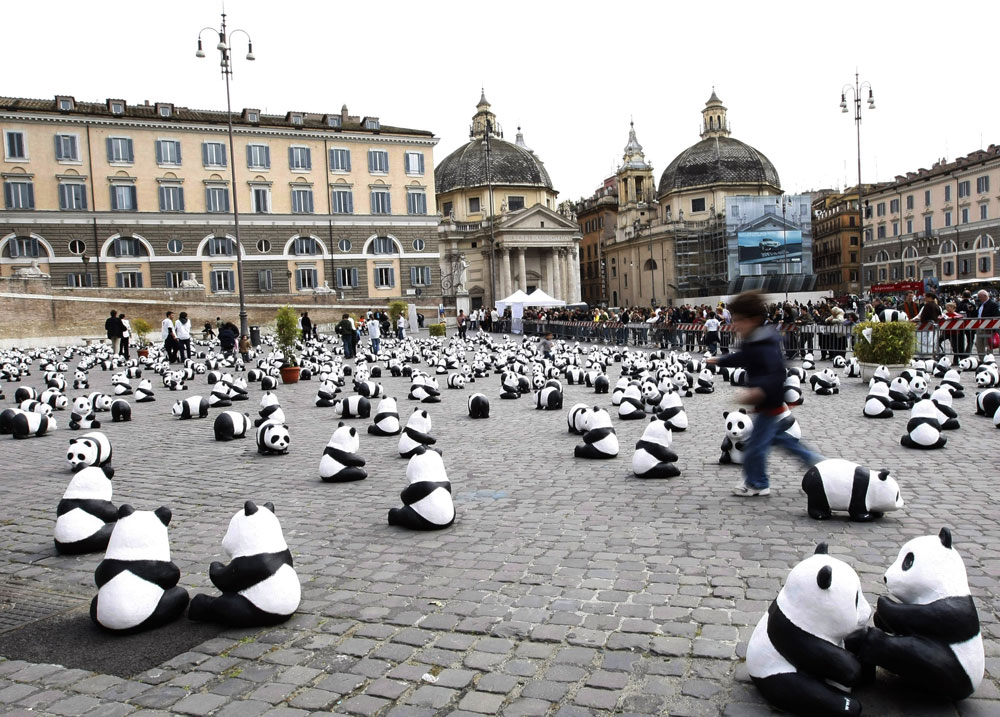 طفل يلعب بين دمى حيوانات الباندا في ساحة روما في ايطاليا