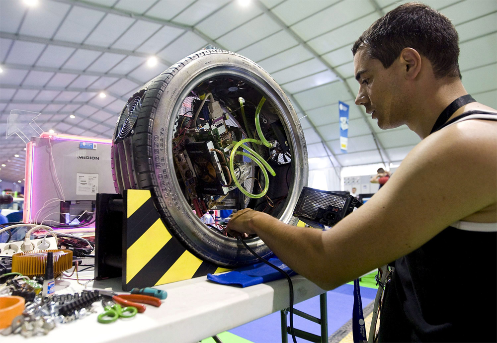 رجل يعرض القرص الصلب لحاسوبه الشخصي والموجود داخل إطار سيارات في مدينة الفنون والعلوم في فالنسيا.