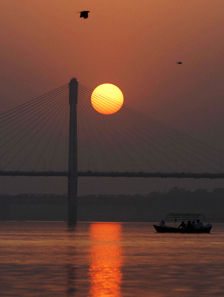 سياح يقطعون نهر يامونا مع غروب شمس مدينة الله أباد في الهند.